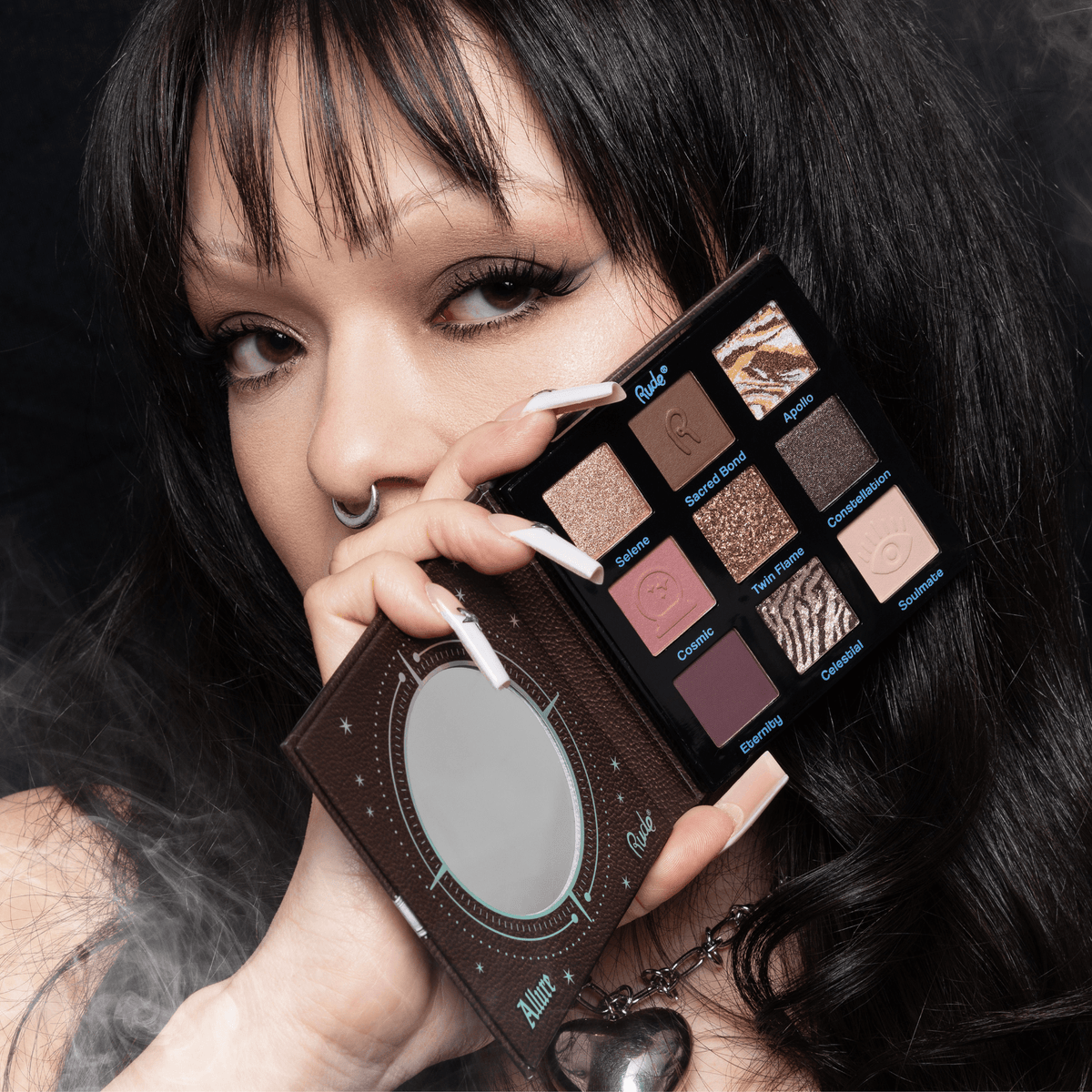 Person holding an eyeshadow palette with a dark background.