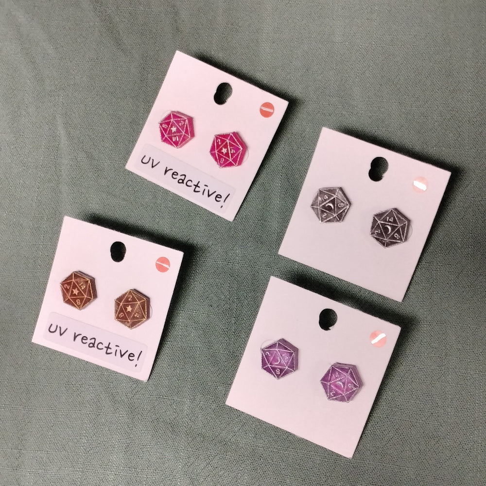 Set of UV reactive earrings on display cards against a gray background