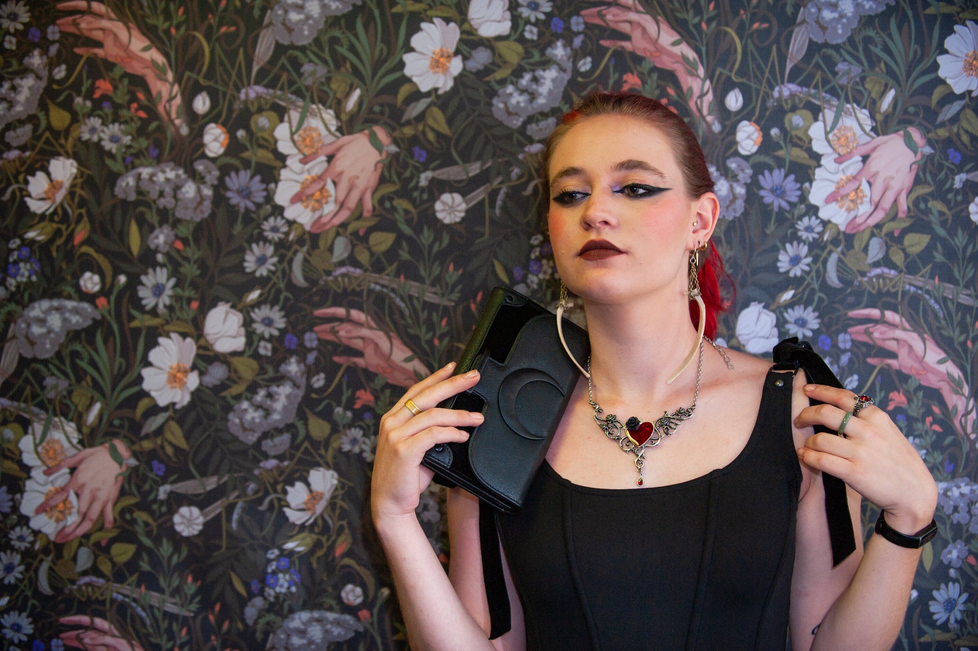 woman standing in front of flowered wallpaper