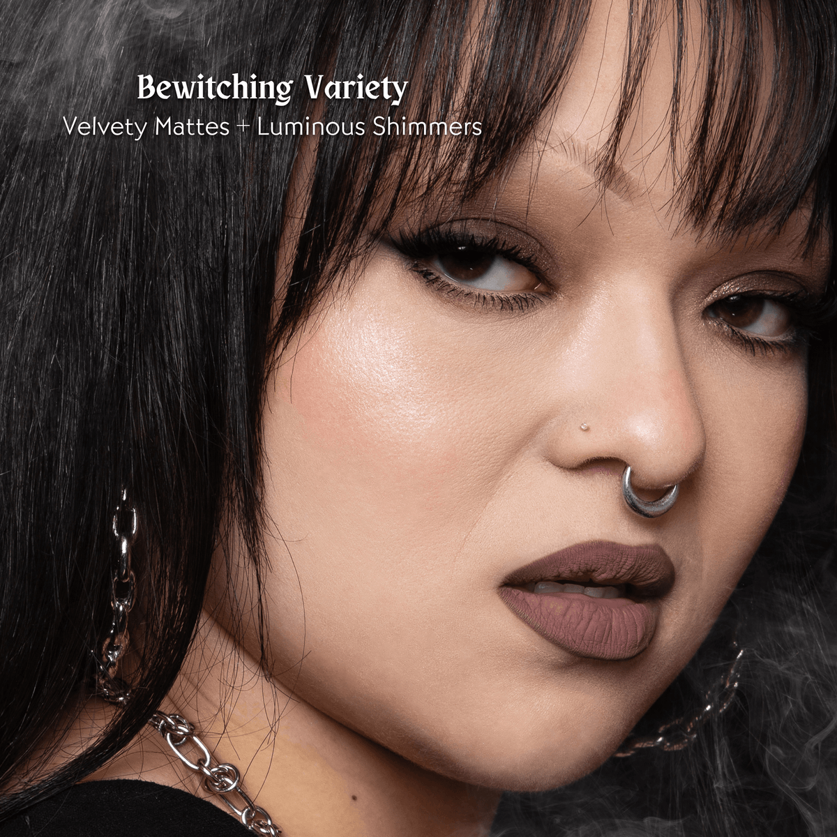 Close-up of a person with dark hair and a silver septum ring, with text &