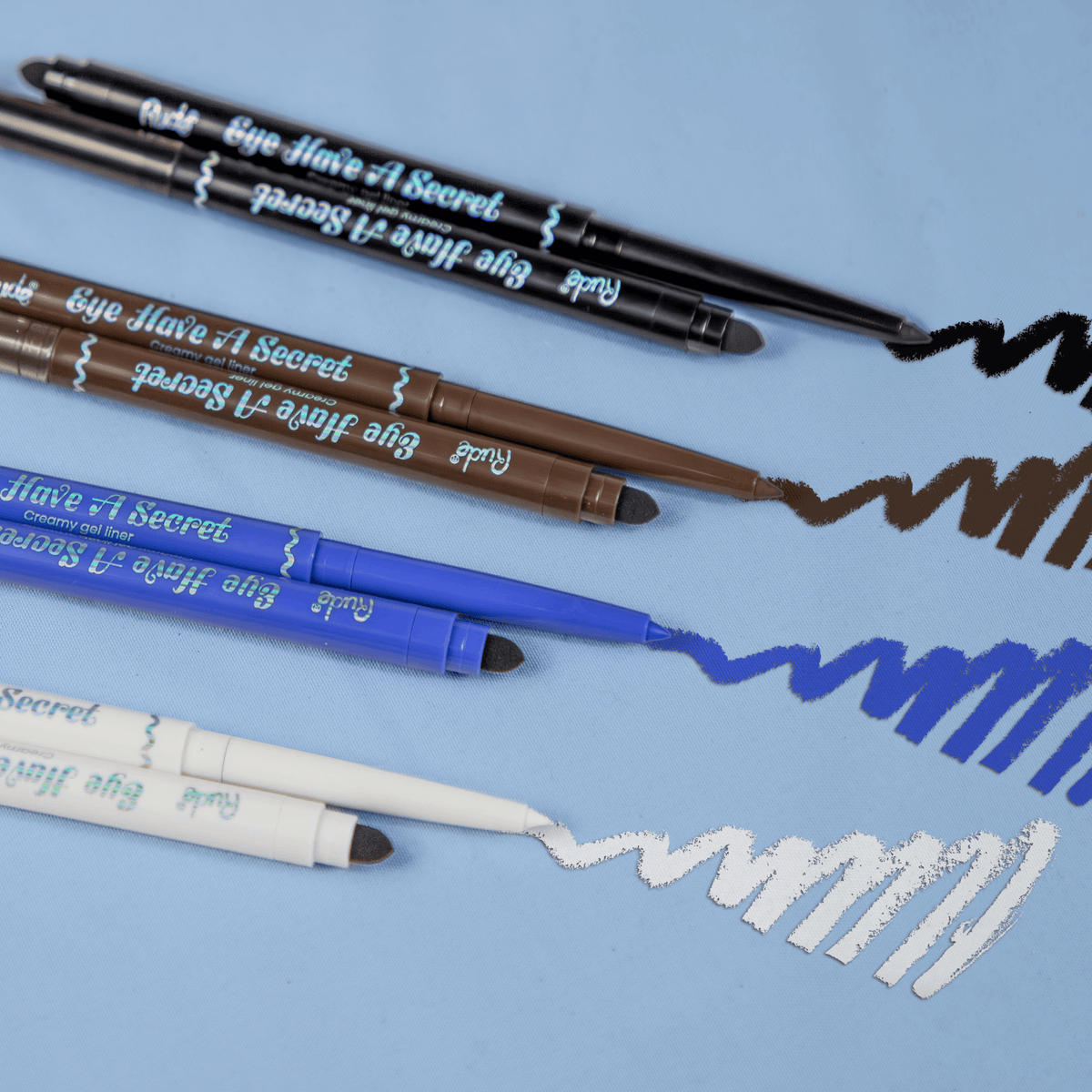 Set of makeup pencils with visible brand name on a blue background