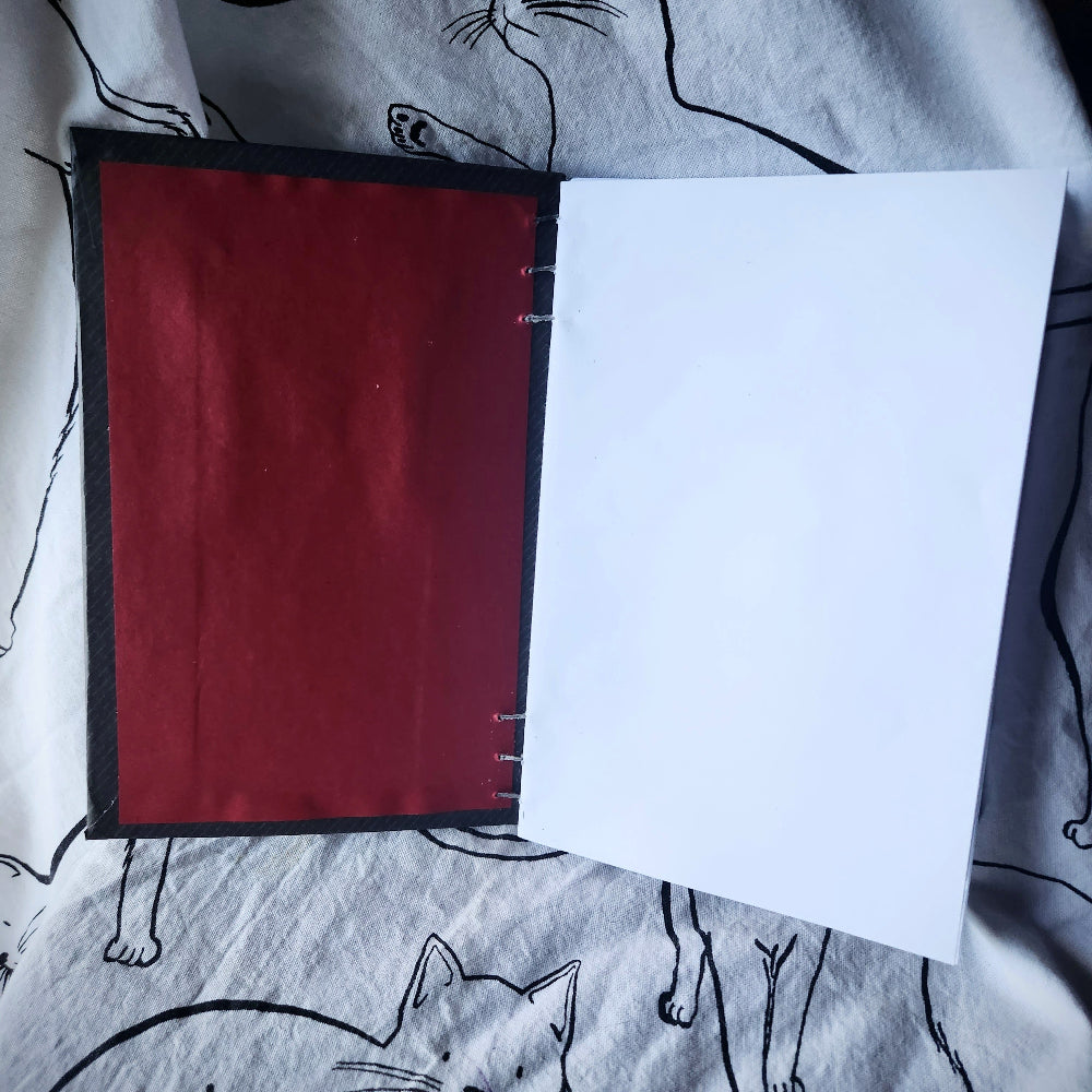 open notebook with red cover and plain white pages on a light background