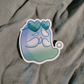 Sticker with a blue and green design on a textured gray surface