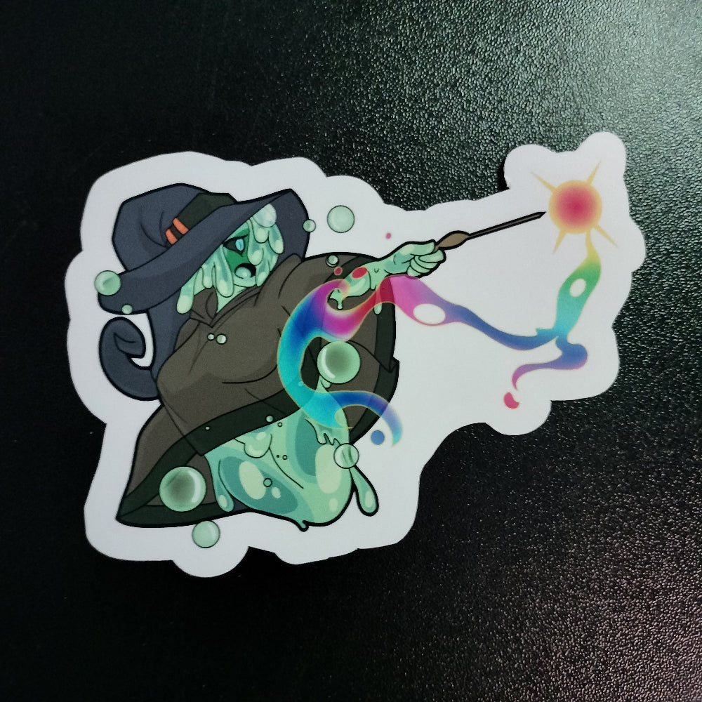 Sticker of a cartoon character in a witch hat with a colorful wand on a black background
