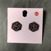 Black d20 dice earrings on a pink card with a gray background
