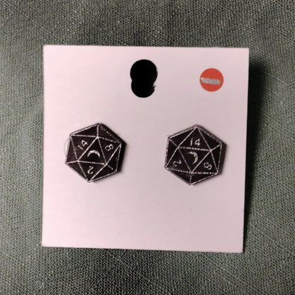 Black d20 dice earrings on a pink card with a gray background