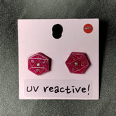 UV reactive earrings on a pink card with a gray background