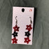 Star-shaped beaded earrings on a display card against a gray background