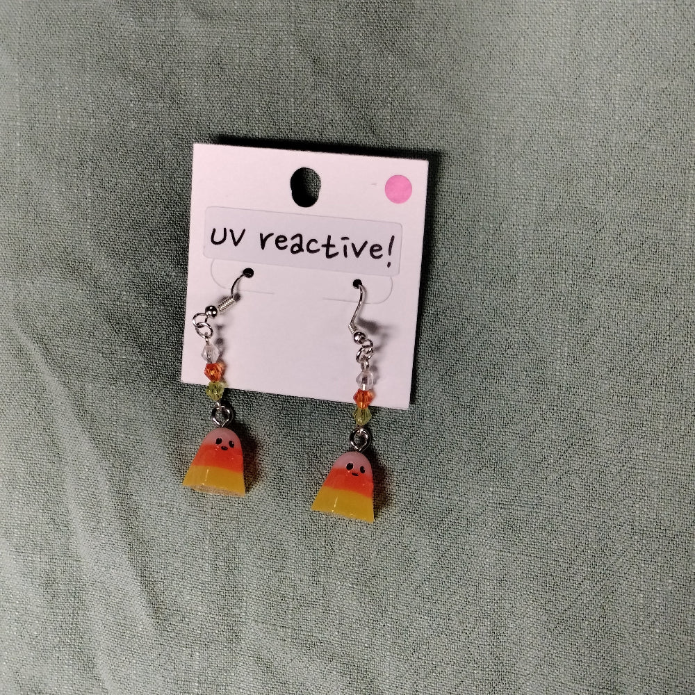 UV reactive candy corn earrings on a gray fabric background