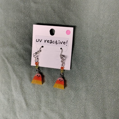 UV reactive candy corn earrings on a gray fabric background