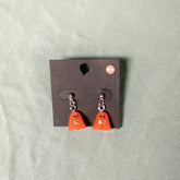 Pair of orange ghost-shaped earrings on a gray card against a light green background